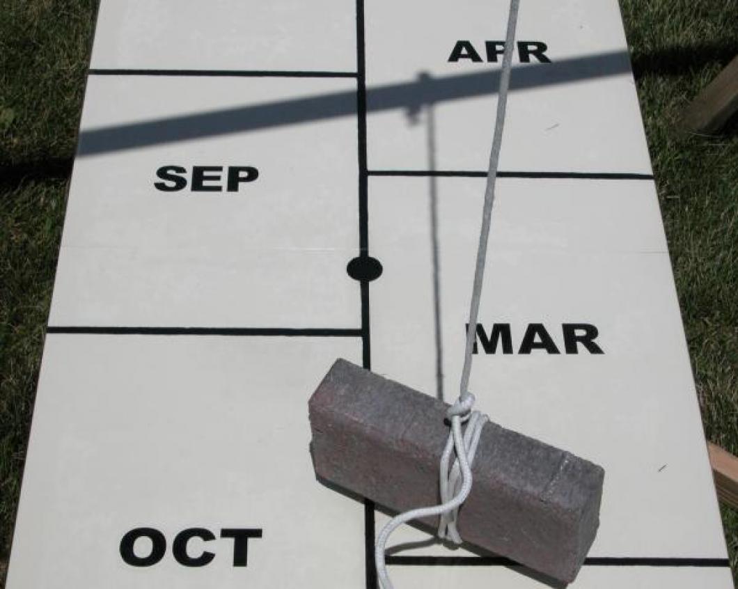Closeup aligning human sundial centre board with shadow of cord at exact time