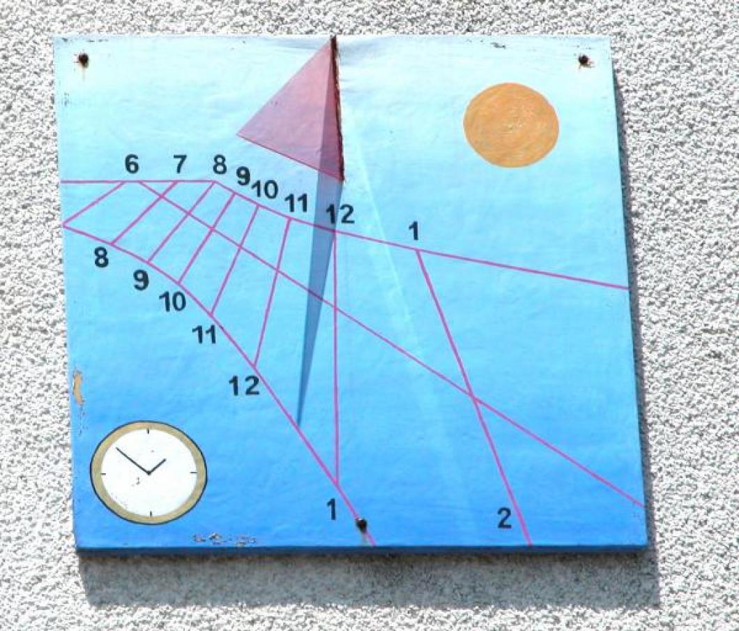 Close-up of wall sundial that faces museum driveway, pink Plexiglas gnomon