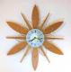 Snider flower-shaped starburst wall clock with teak wood rays and brass-plated rod loops (ca. 1970, battery movement, a Michael Snider design)