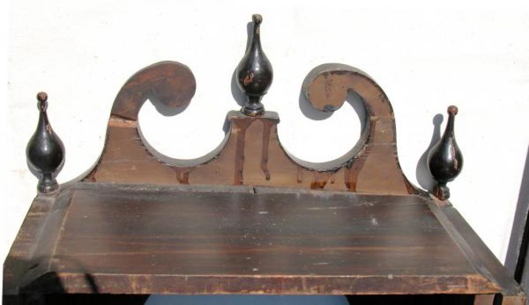 The back of the scrolls at the top of the pine wood hood (repairs of horizontal breaks are visible).