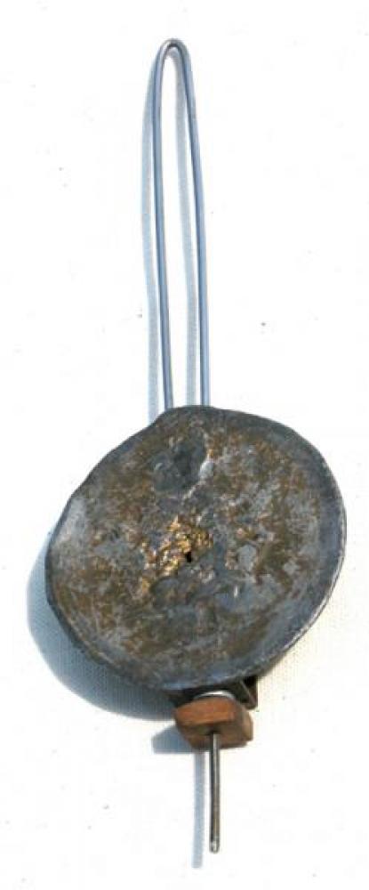 The flat side of the cast lead pendulum bob, set facing the back wall; note the square wood nut.
