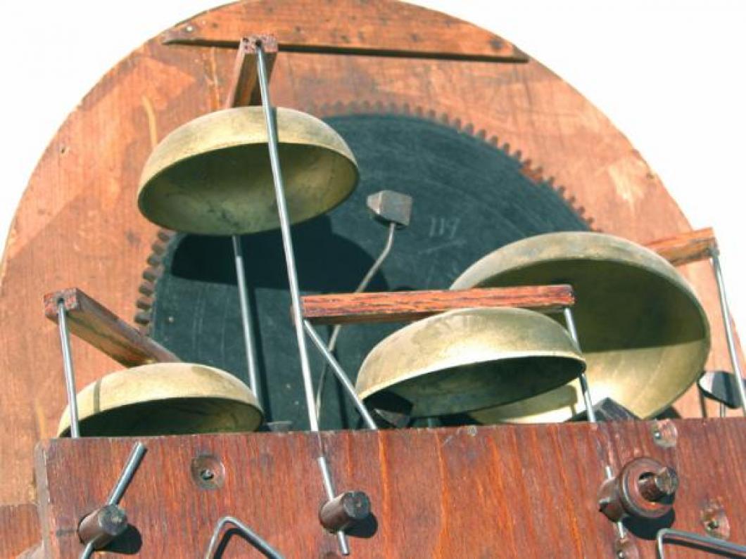 Looking up at the set of four replacement cast bells mounted in the top edges of the two wood plates.